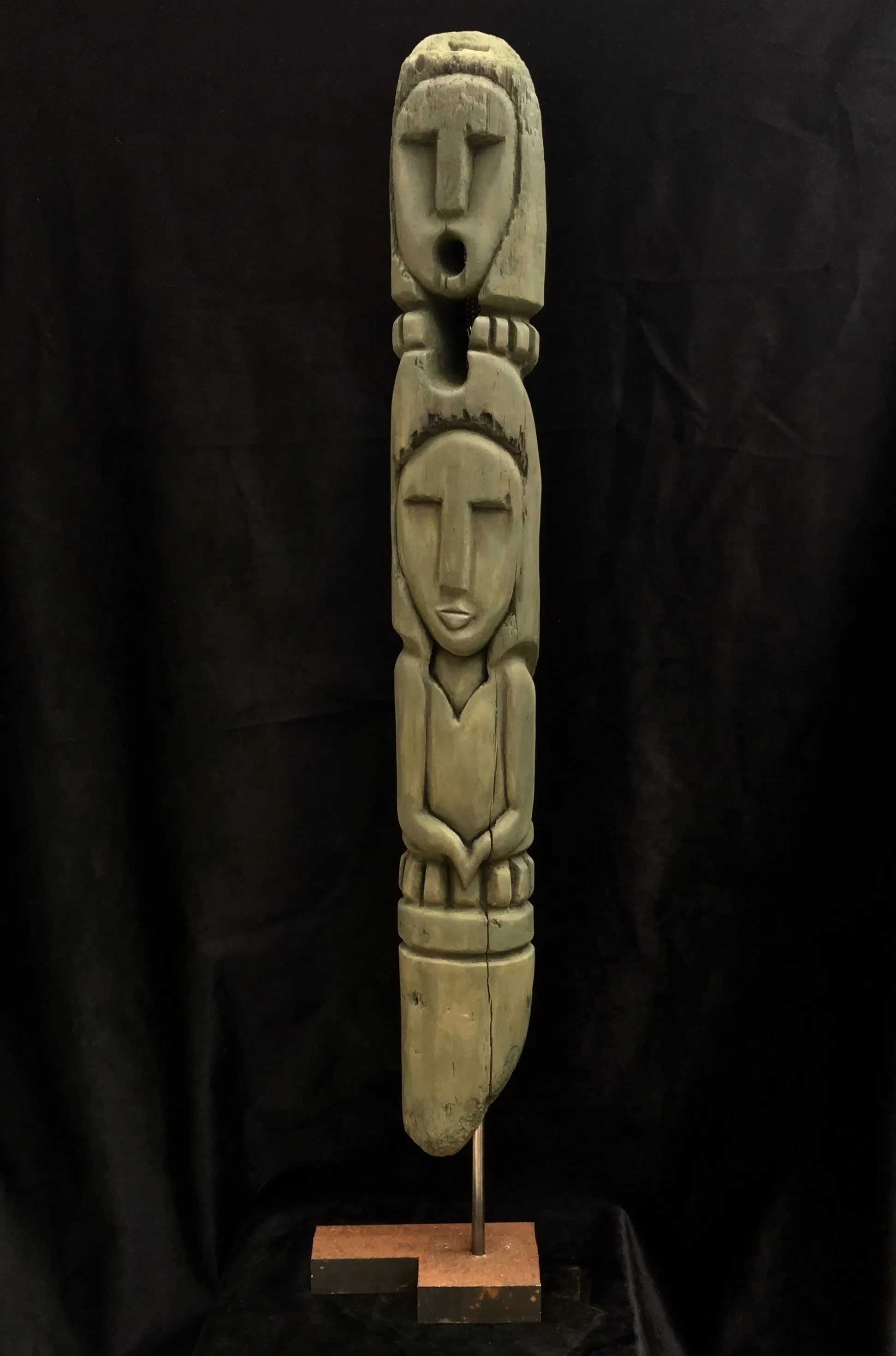 A wooden totem pole featuring intricate carvings and two people