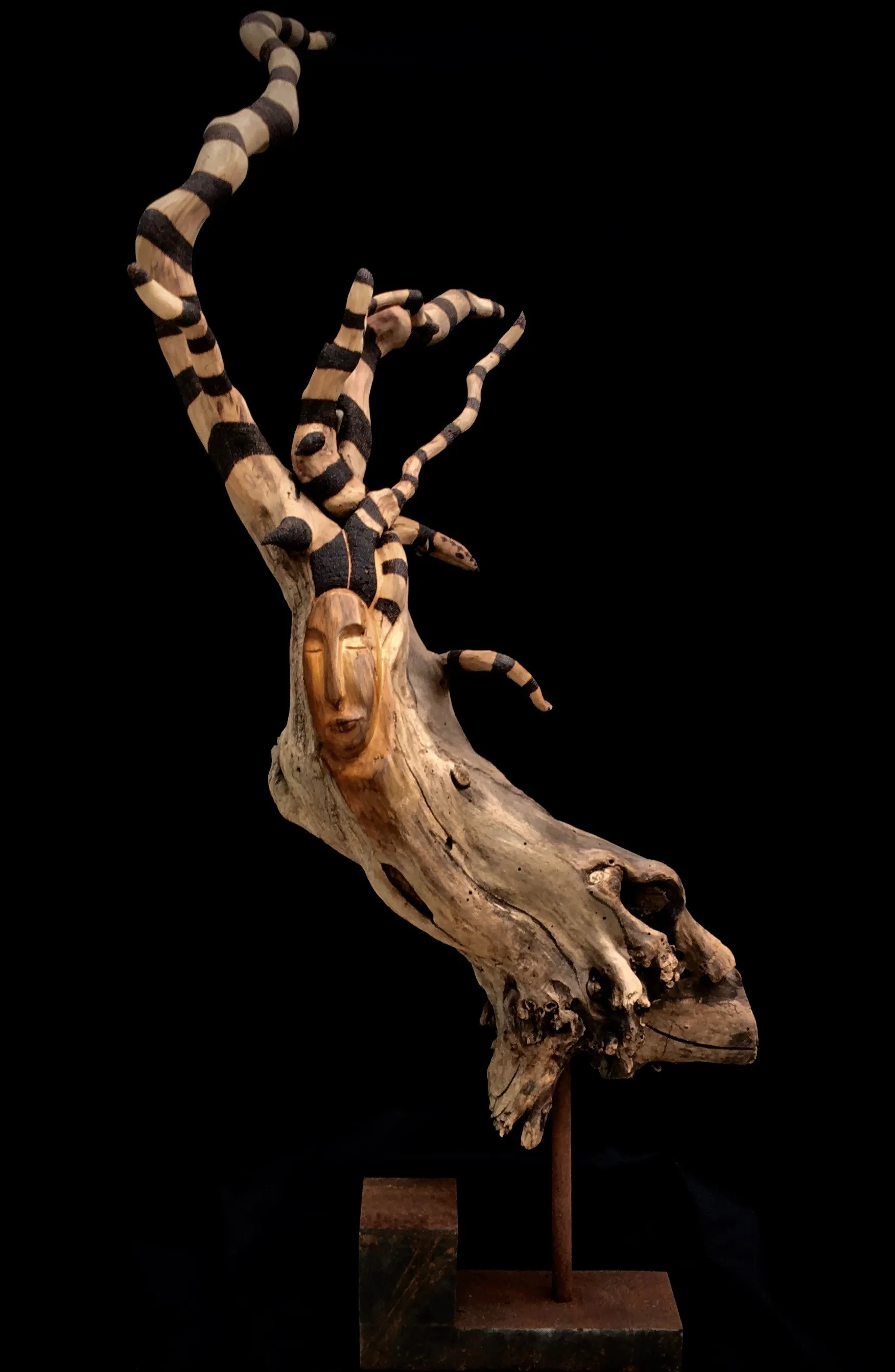 A sculpture of a woman with her head resting on a tree branch