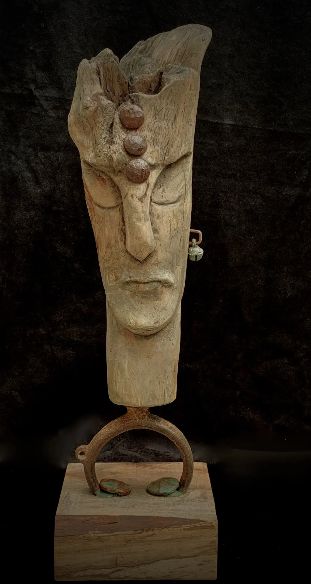 A wooden sculpture of a head, featuring a stone-like texture