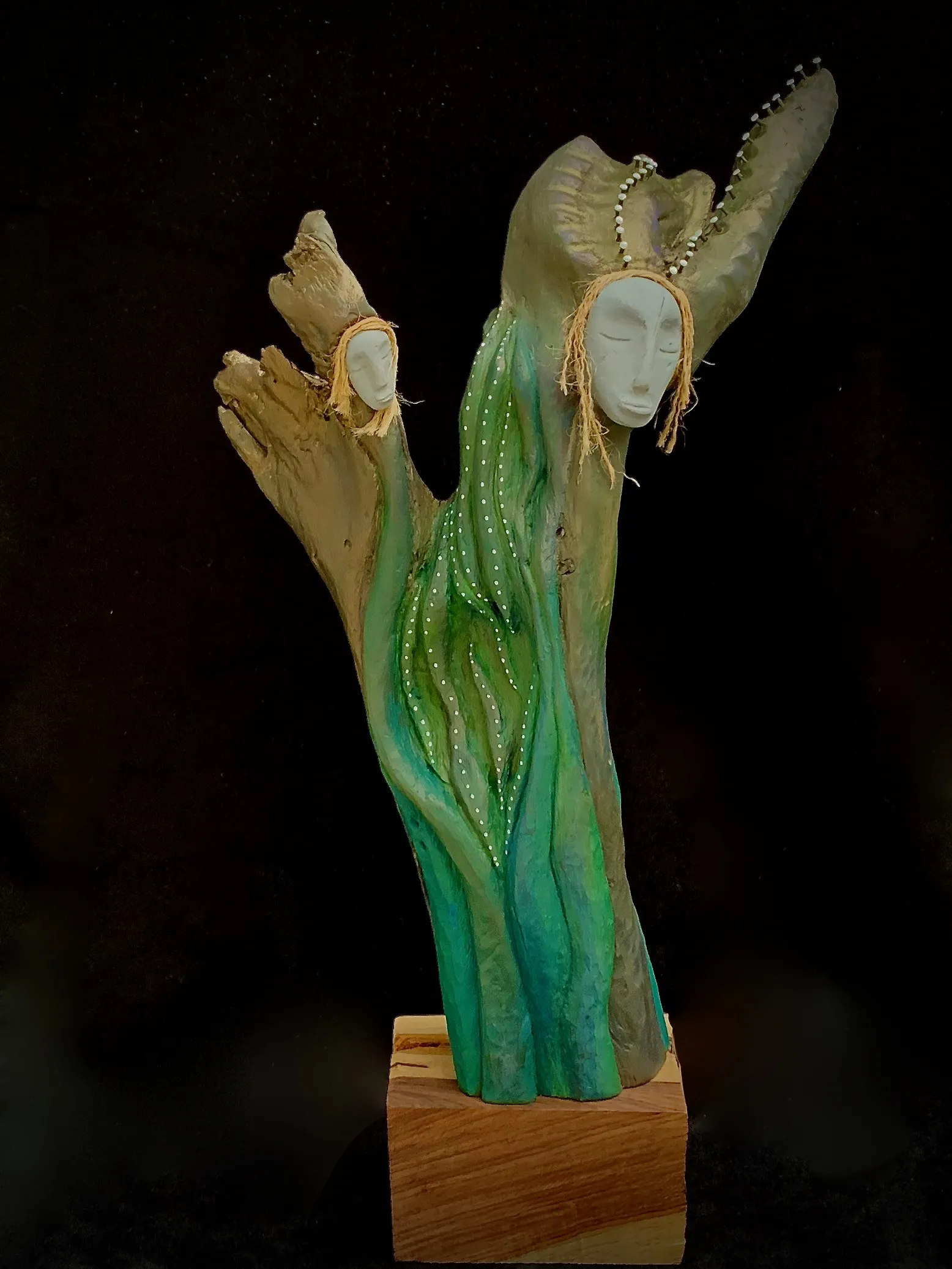 A wood sculpture of a woman with a green head