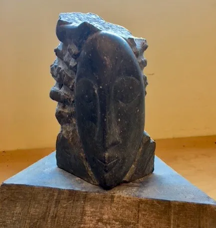 A sleek black sculpture resting on a simple wooden block