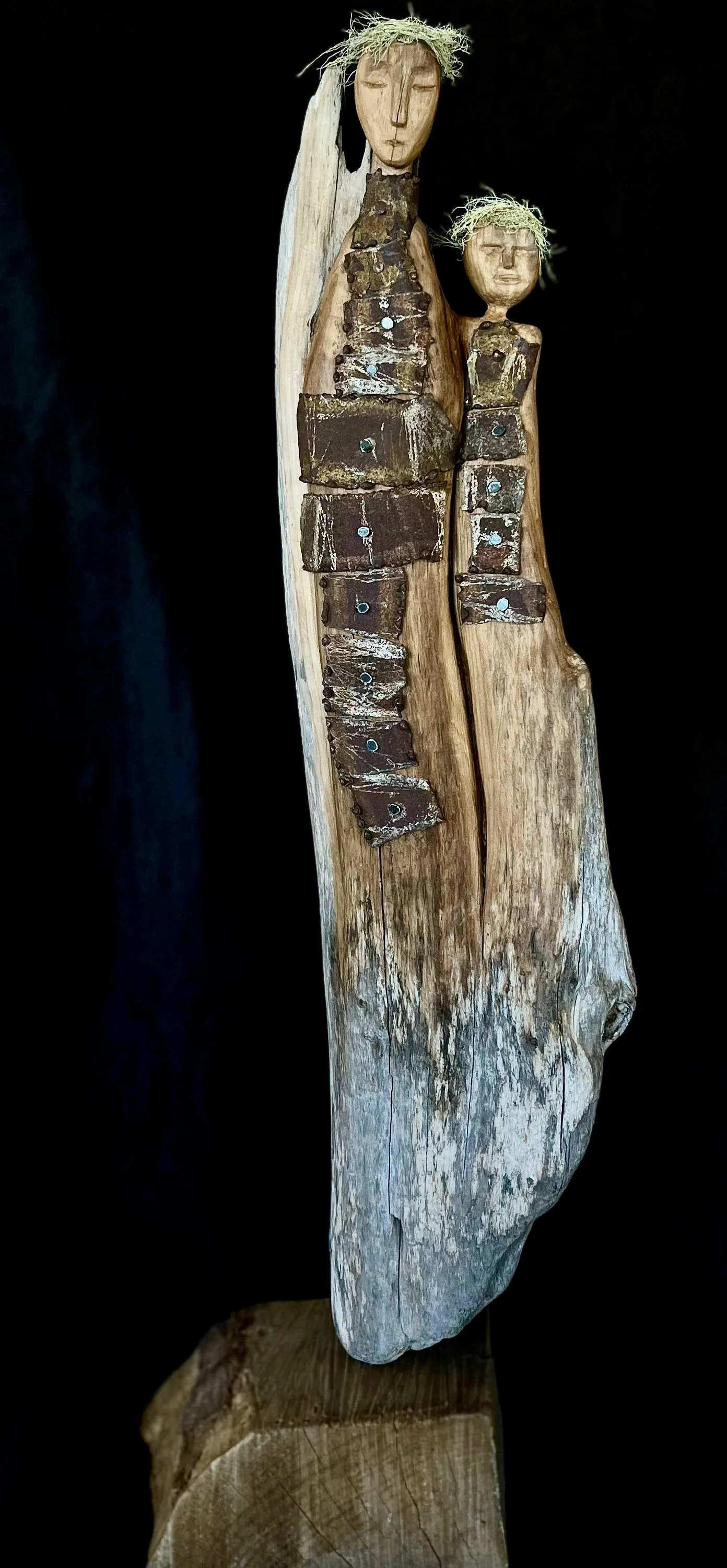 A wooden artwork featuring two individuals on a rock