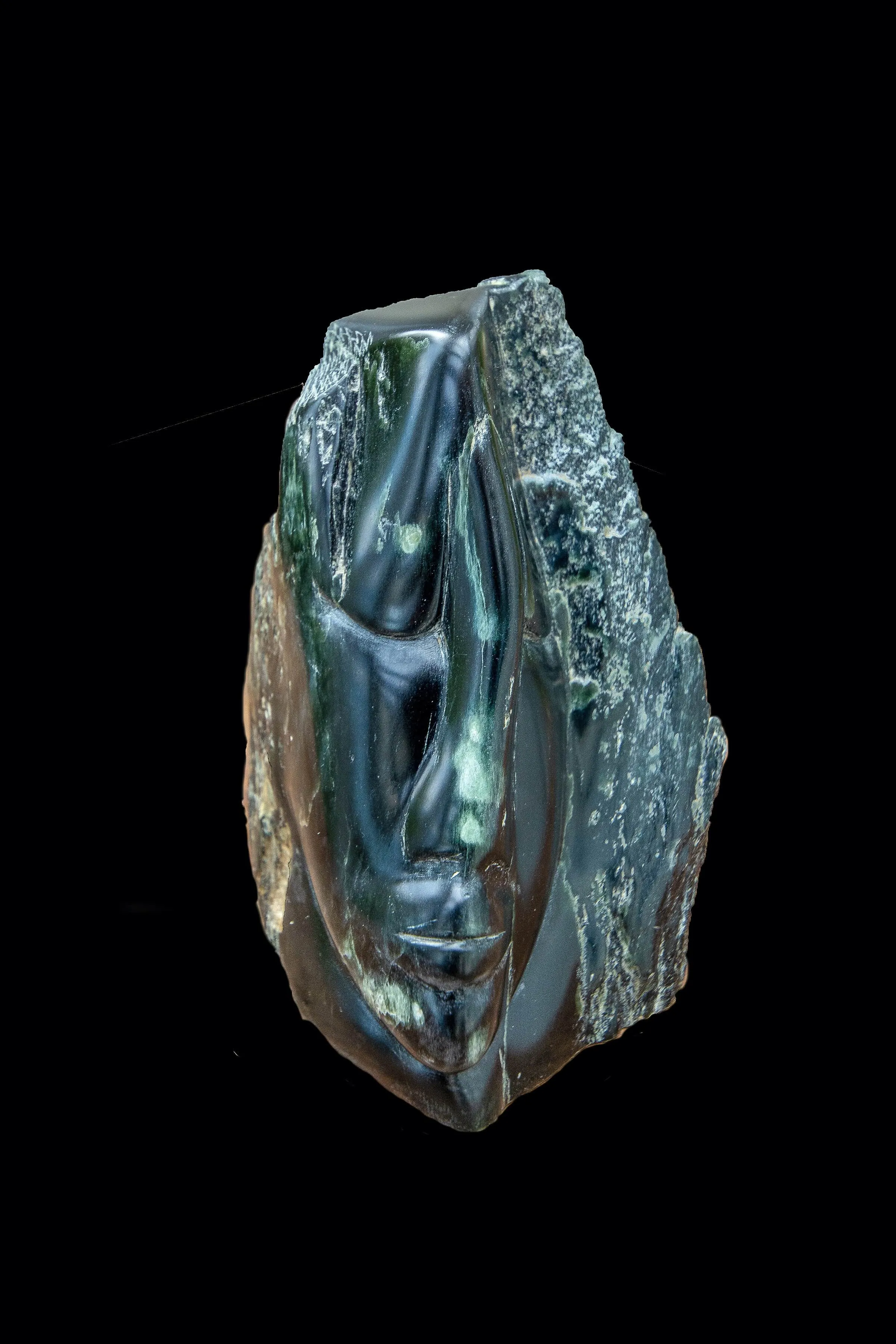 A green stone sculpture featuring a carved face